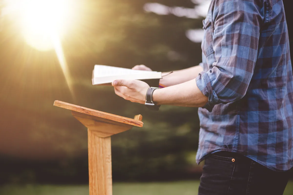 Pastor speaking passionately from the pulpit with open Scriptures and warm auditorium lighting
