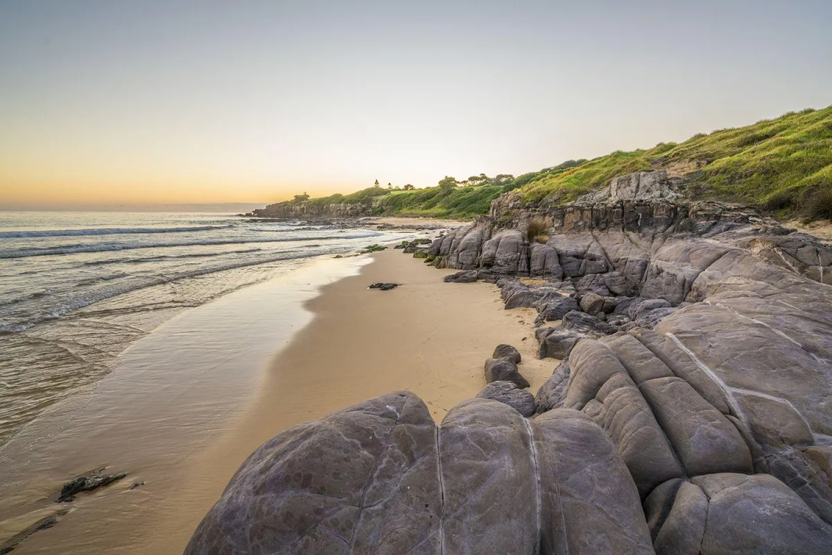Sunset casts gold light over mountains and water.