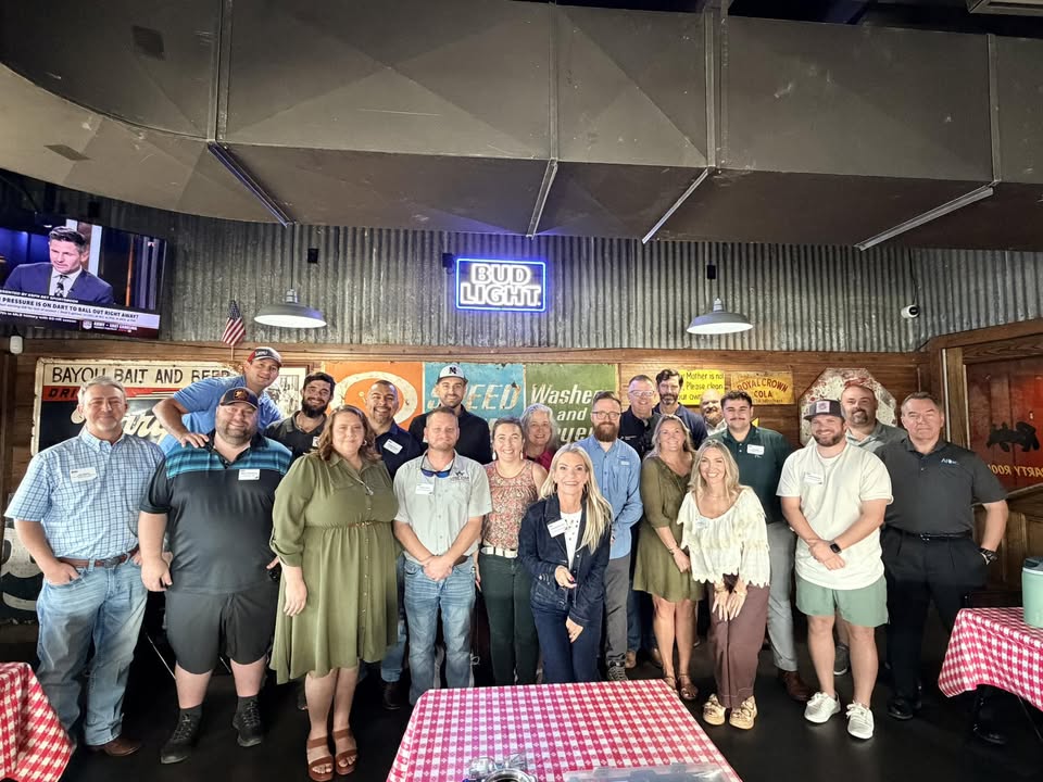 A diverse group of small business owners exchanging business cards and smiling in a bright, modern coworking space, with natural light and a welcoming atmosphere. Each person is engaged in conversation, representing various industries and backgrounds.