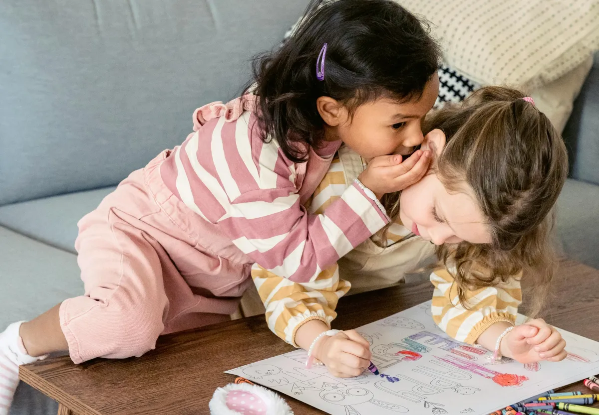Image of a child whispering her thoughts and encouragement to another child.