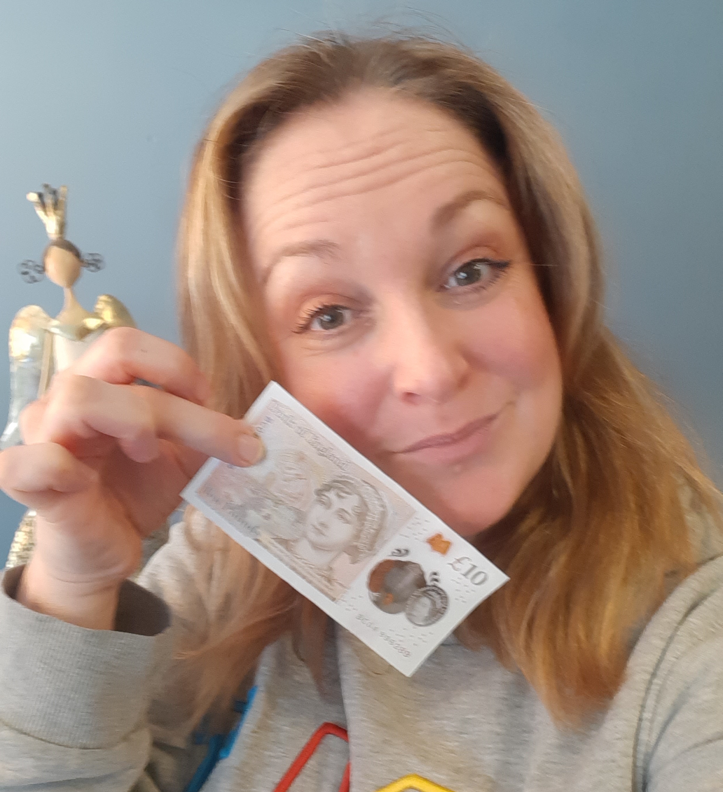 Sam holding a £10 note, smiling