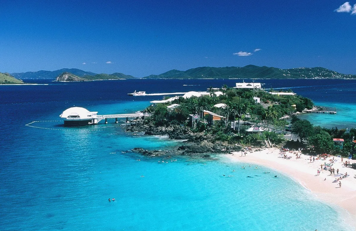 Wide-angle view of St. Thomas harbor at golden hour with ferries and planes
