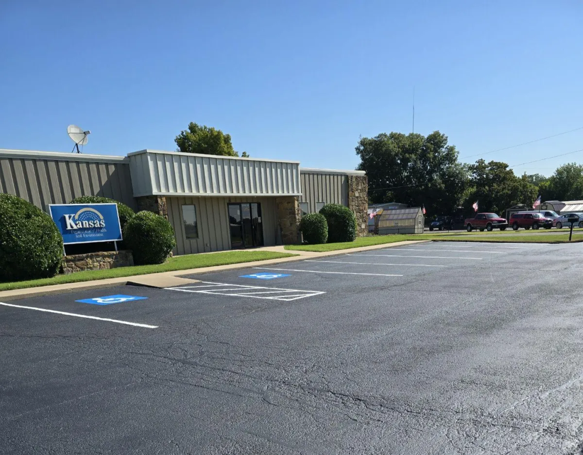 Crew paving a rural Kansas driveway at sunset with asphalt roller