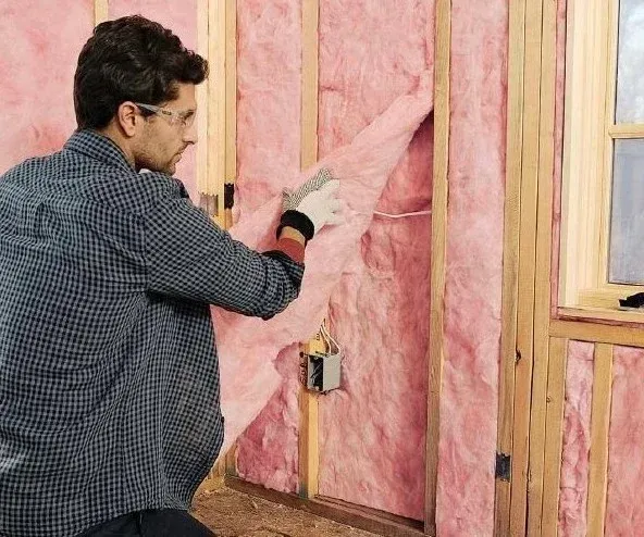 Contractor properly installing fiberglass batt insulation in wall cavities for optimal energy performance in Astor, FL