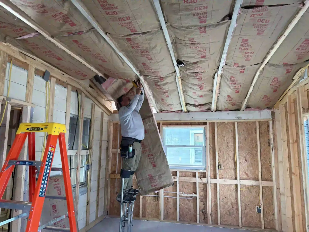 Fiberglass batt insulation being carefully installed between ceiling joists in a home near Astor, FL to ensure proper R-value and energy efficiency