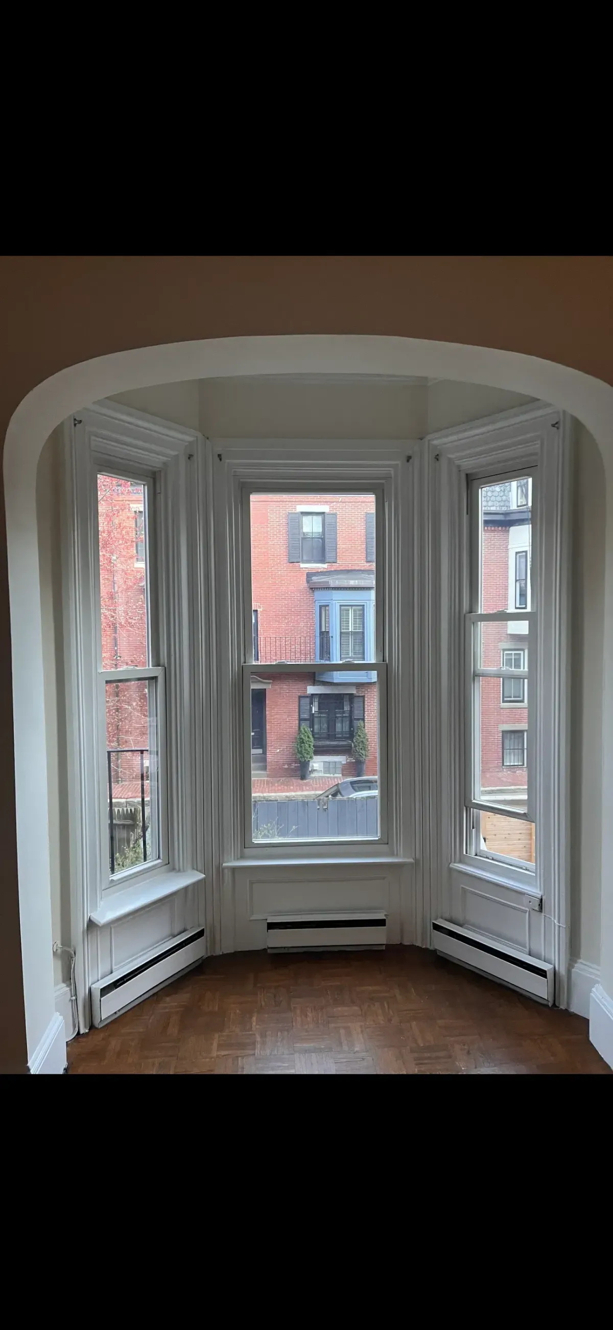 Bay window trim painting in Arlington Center MA older home with detailed white casing and plaster walls