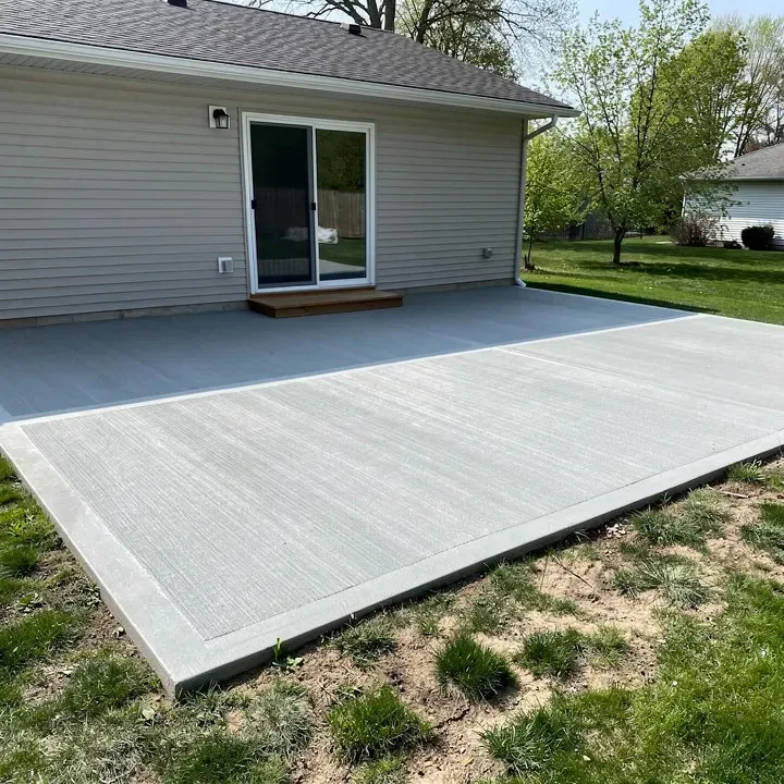 Freshly finished concrete patio slab with a straight downspout along the wall in Sheboygan, Wisconsin.