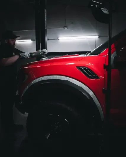 A man polishing a red car