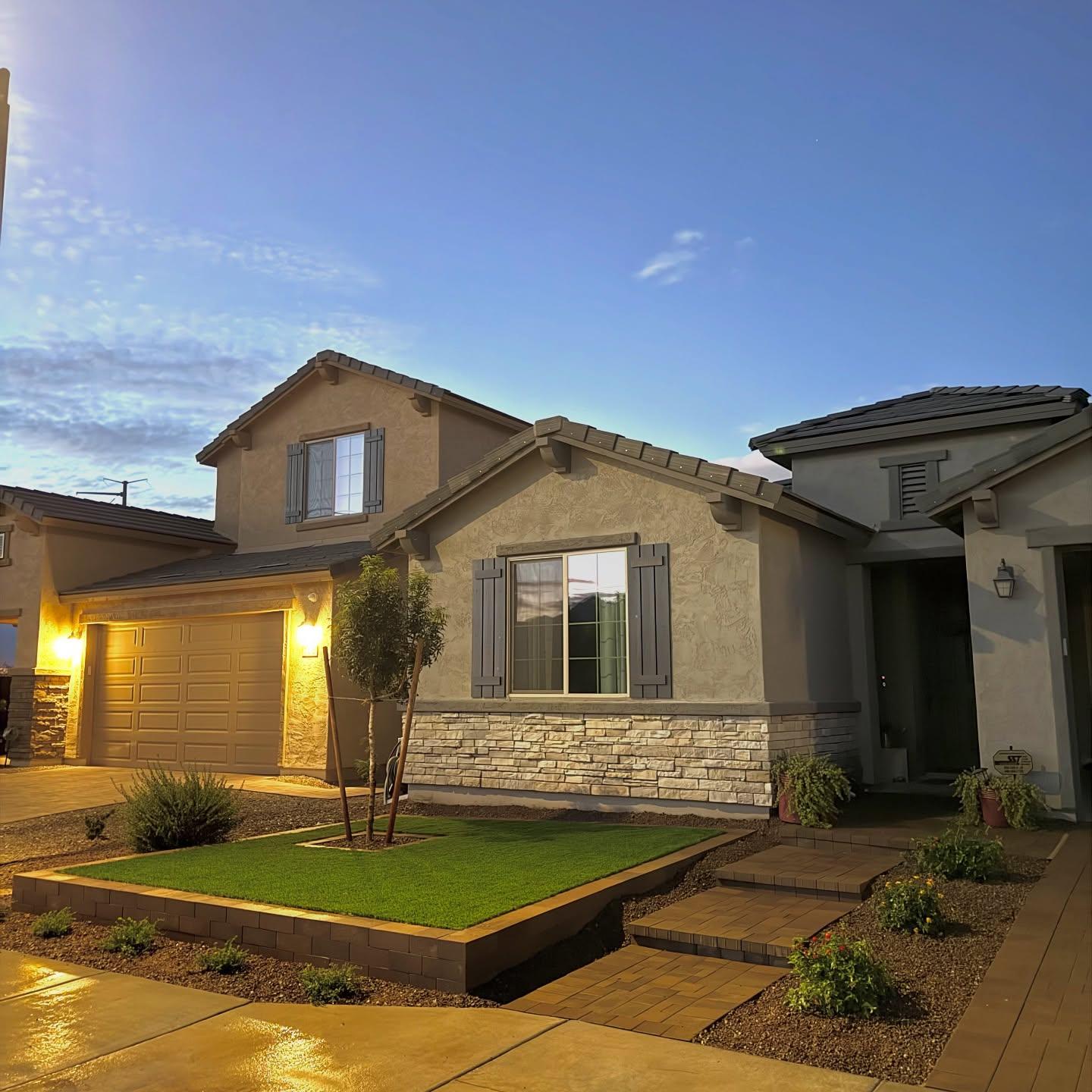 Dusk front yard with raised turf planter and paver-capped retaining wall