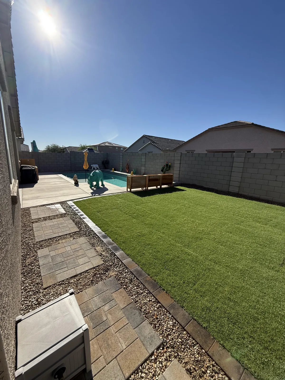 Backyard with lush green lawn, travertine paver patio, and pool, turf and sod installation Phoenix AZ