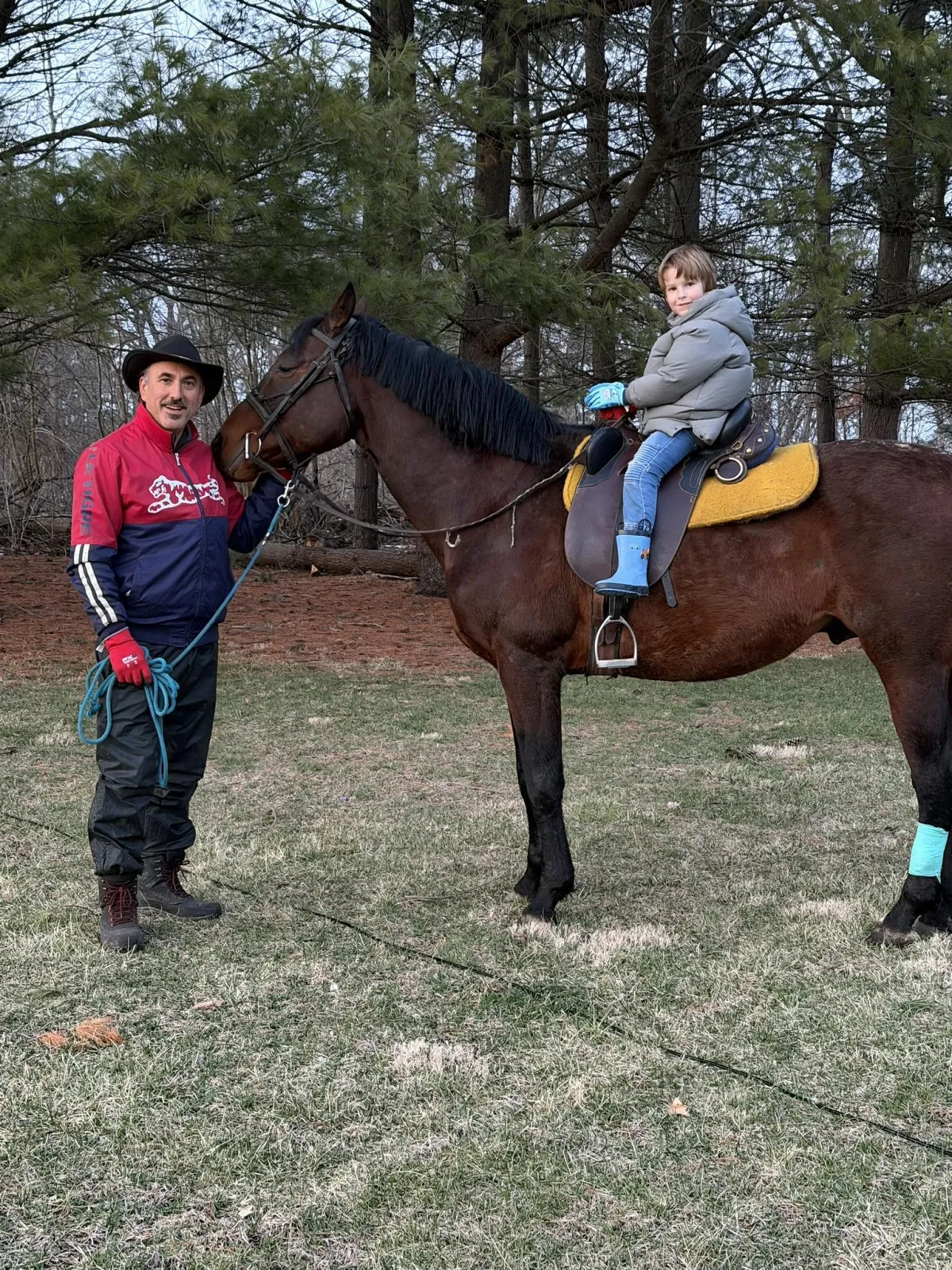 Photo of boy on brown horse held by the owner.