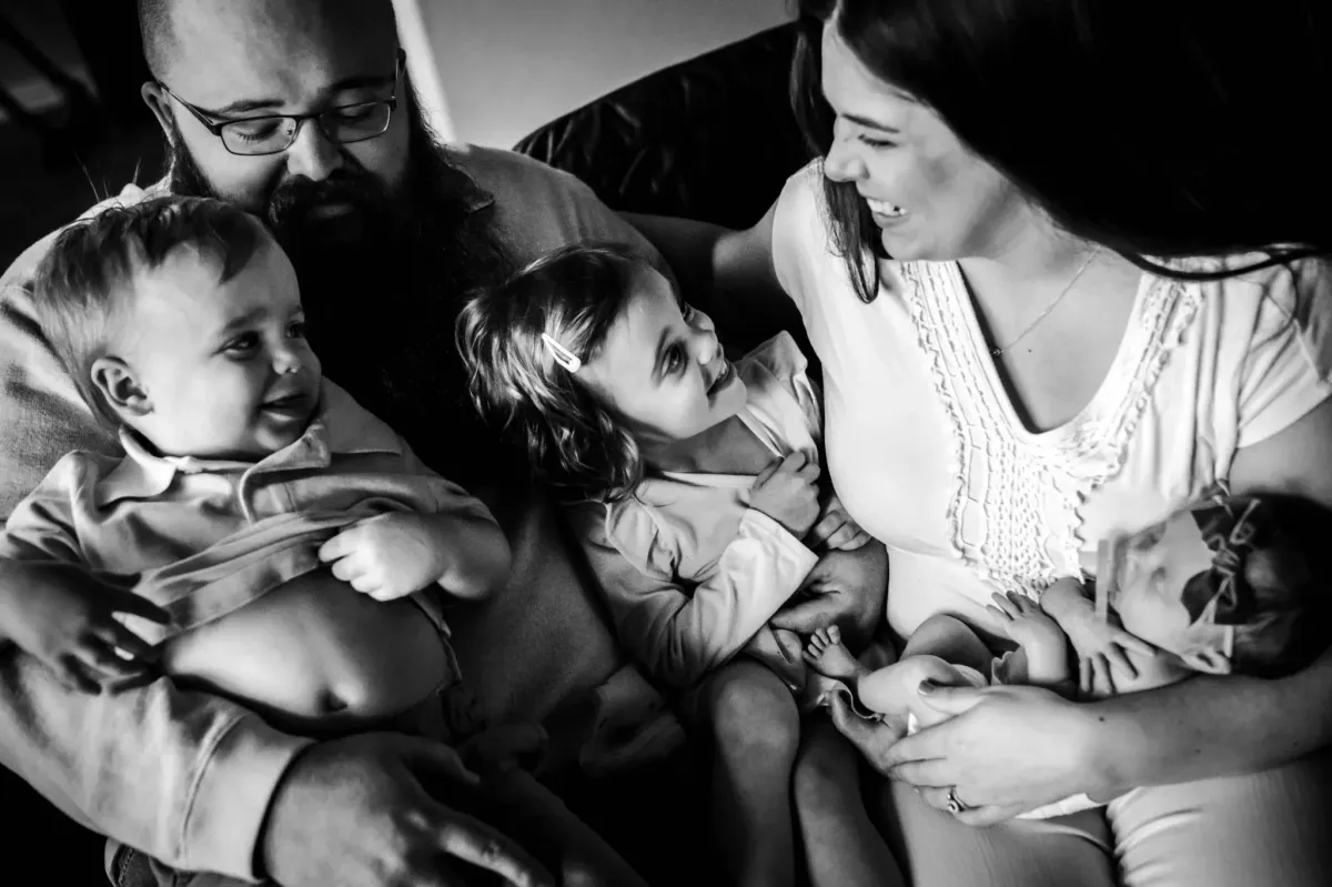 Black and white documentary style photography of a midwife consulting with a mother