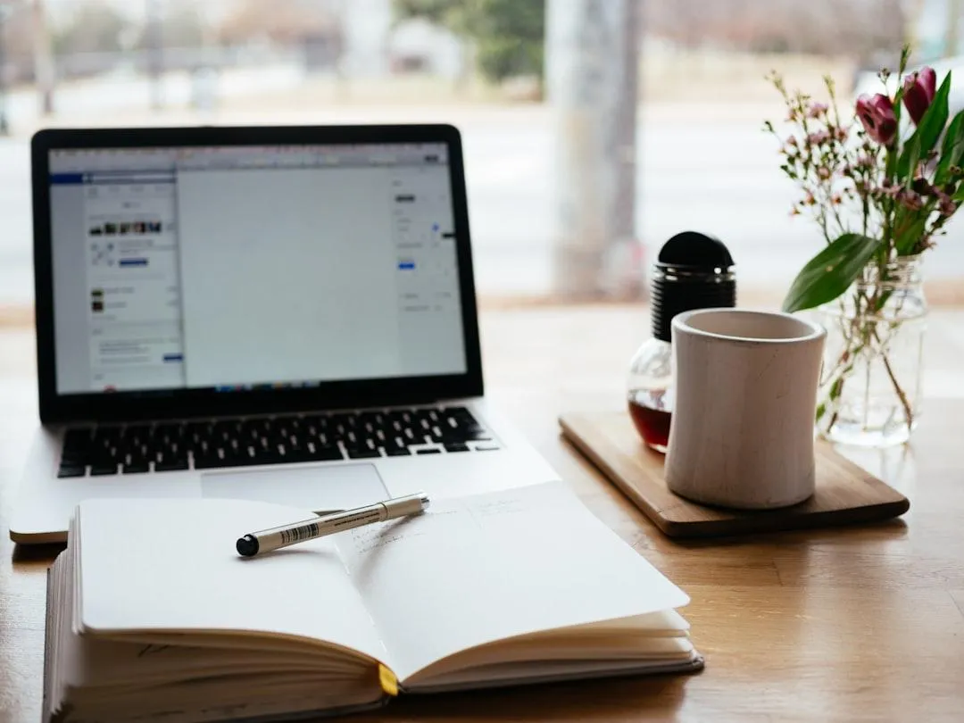 A smiling female consultant in her 30s, sitting at a desk with a laptop and headset, assisting a client via video call. The background shows a tidy, modern office with blue accents and motivational posters. The consultant appears attentive and supportive. Modern, clean photographic style.