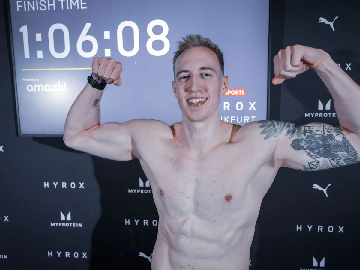 Robinson Bentler jubelt im Ziel von HYROX Frankfurt, im Hintergrund die Finish Time 1:06:08