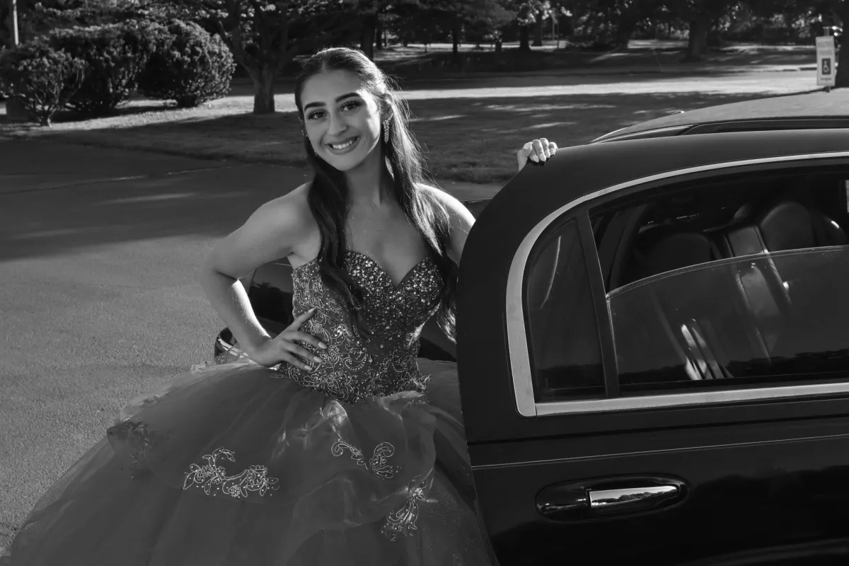 Woman Wearing a Gown and Smiling at the Camera Before Getting Into Limousine