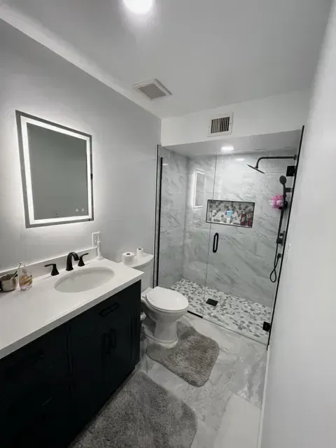 Modern bathroom featuring a glass shower, vanity, and gray decor.