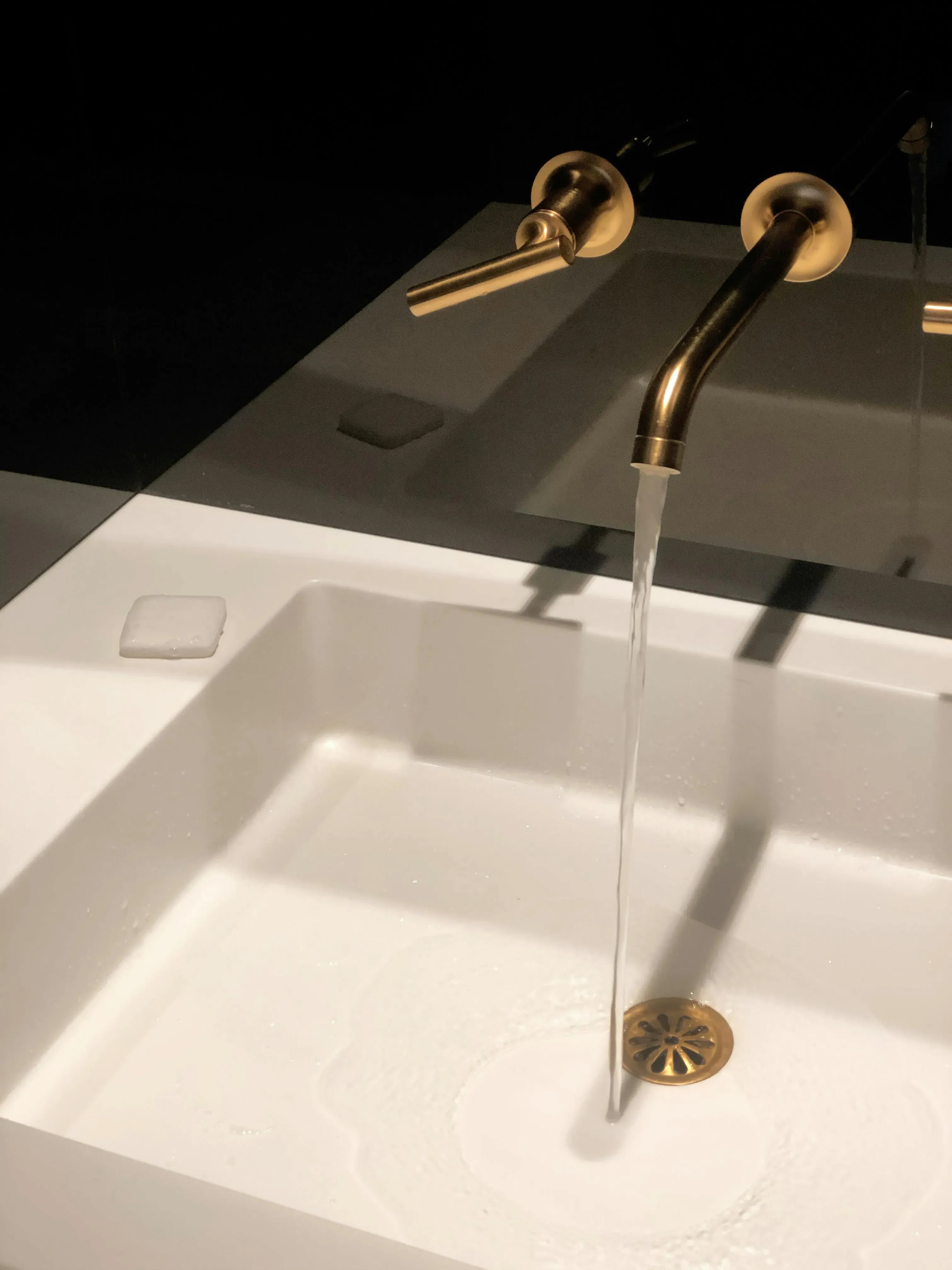 Modern sink with a gold faucet and running water.