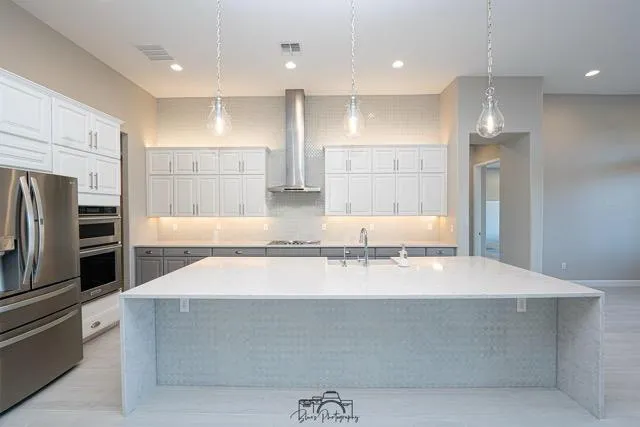 ### Key Elements

**Main Subjects**  
- Modern kitchen design  
- Central island with seating  

**Objects**  
- Stainless steel appliances (refrigerator, oven, microwave)  
- White cabinetry with a sleek finish  
- Quartz countertop  

**Notable Features**  
- Pendant lighting above the island  
- Neutral color palette (grays and whites)  
- Open layout with ample natural light  

**Text/Symbols**  
- No visible text or symbols  

### Overall Mood/Theme  
The image conveys a contemporary and inviting atmosphere, emphasizing functionality and elegance in a spacious kitchen setting. The use of light colors and modern fixtures creates a bright and airy feel.