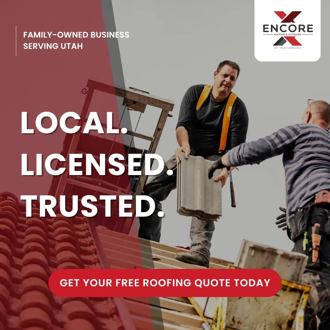 Two workers installing roofing tiles on a house with a red tiled roof.