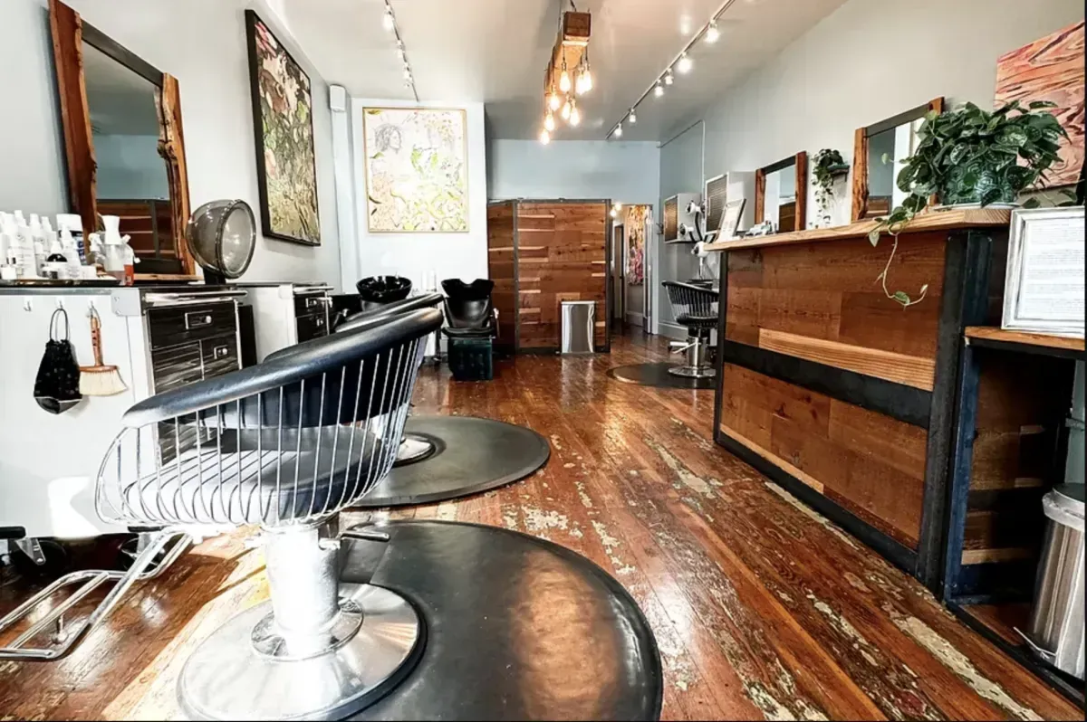 Stylish hair salon with rustic wooden floors, chairs, mirrors, and reception area.