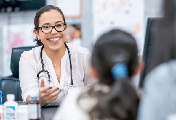 Smiling female doctor talking to patients in a medical office.
