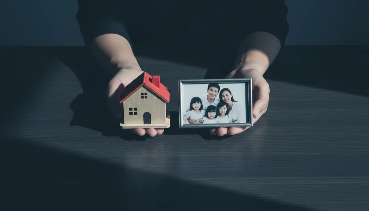 Hands holding a house model and family photo symbolizing financial security Hands holding a house model and family photo symbolizing financial security