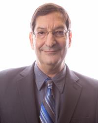 Harry Krause, a middle-aged man with salt-and-pepper hair and a warm smile, stands in a home office with bookshelves and family photos, exuding trust and approachability.