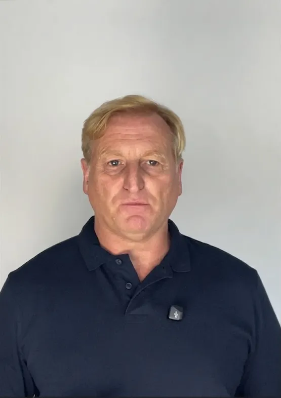 Portrait of Phil in a navy polo against a light wall (founder photo).