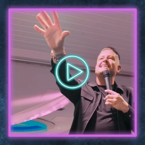 Video thumbnail showing a man speaking into a microphone with his hand raised, enclosed in a bright neon border