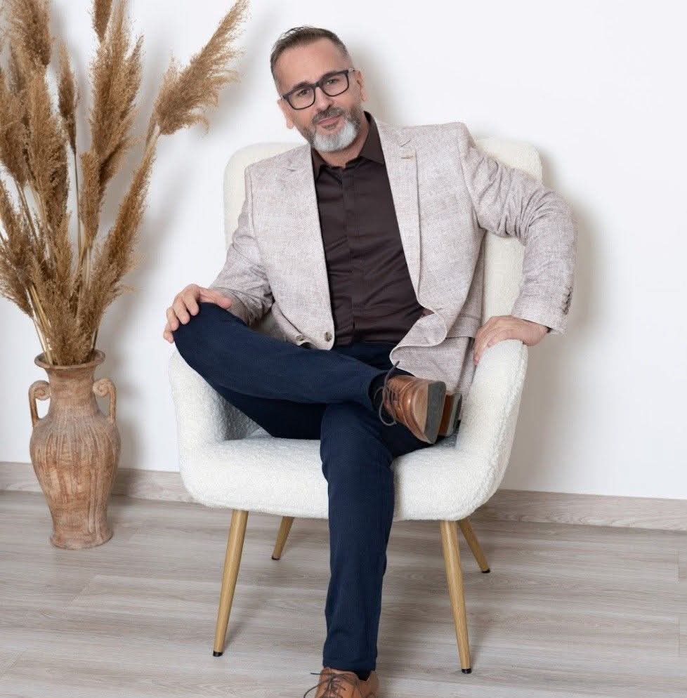 Orcsik Imre portréja egy világos, meleg hangulatú térben ülve