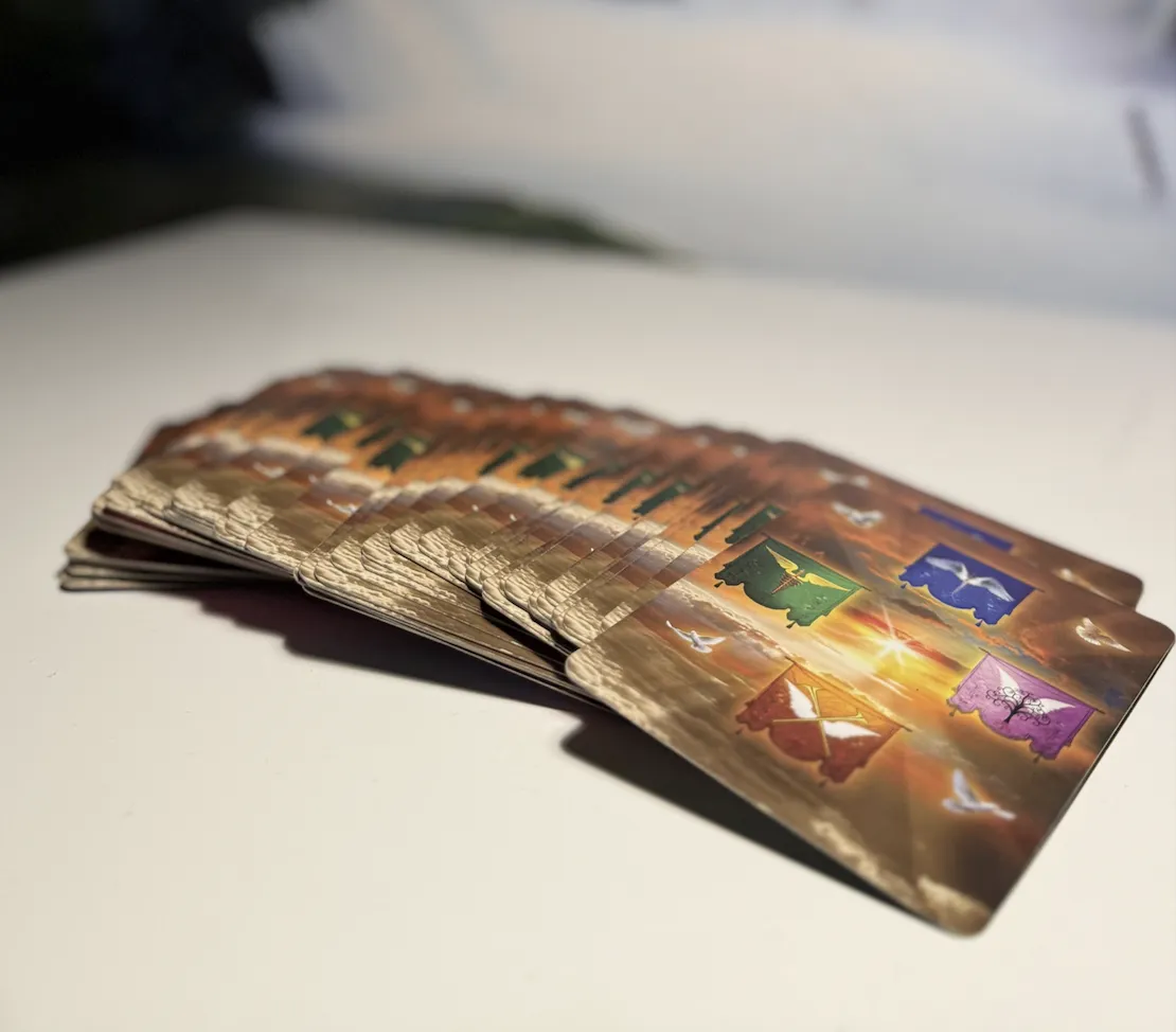 En kvinna i mjukt ljus som stilla betraktar ett tarotkort med intuitiv närvaro