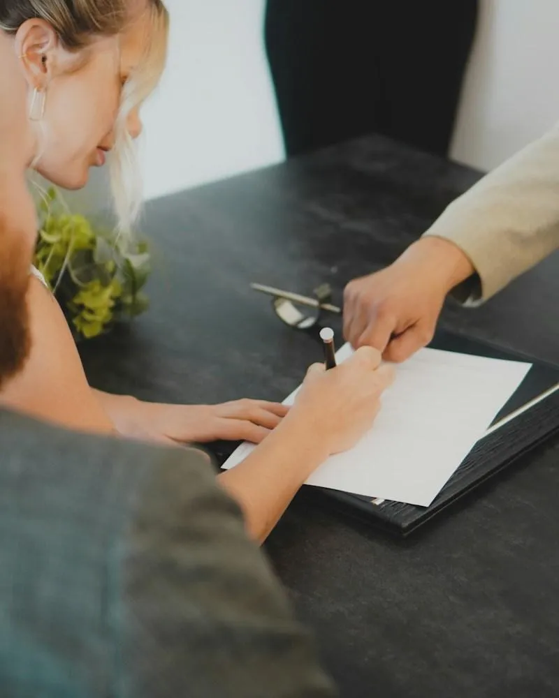 Couple signing home sale closing paperwork at desk