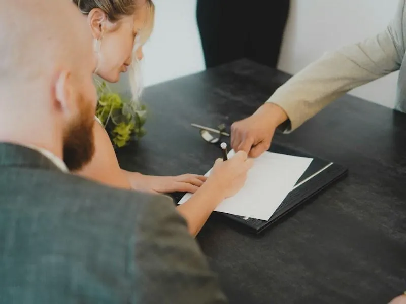 A couple reviewing and signing a home sale contract at a desk