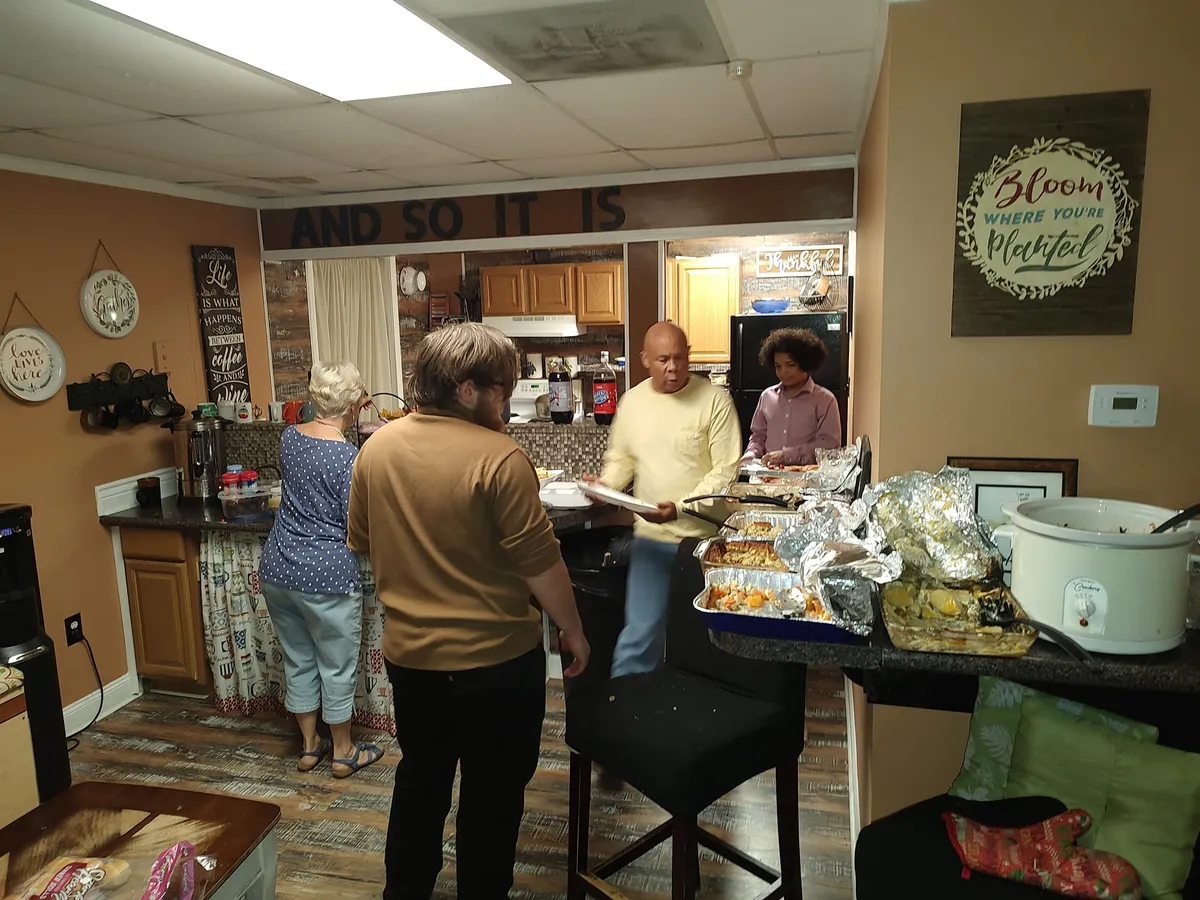 Community members serving food in the kitchen area at the potluck