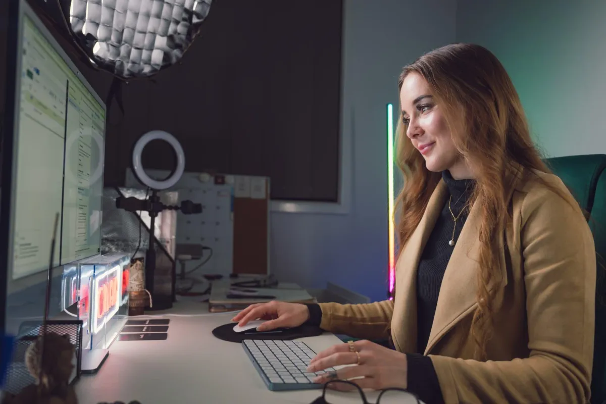 Woman working confidently at a content creator desk with dual monitors and ring light