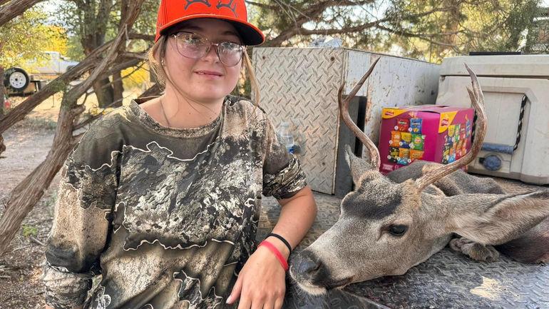 Young hunter posing with harvested mule deer