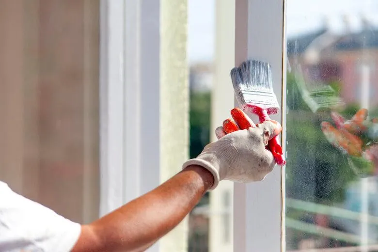 Painter carefully applying tape to a wall edge