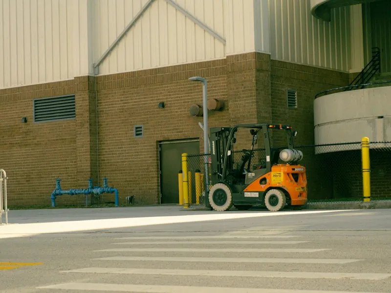 Orange forklift parked outside industrial building