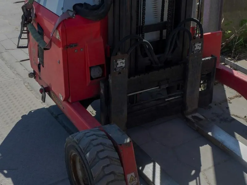 Red and gray forklift with large tire on pavement