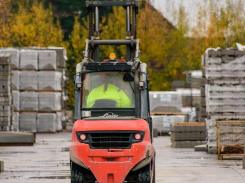 Red forklift driving on a wet construction site