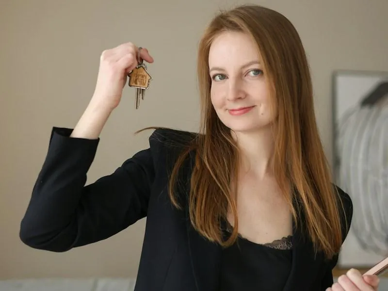 Woman in suit holding keys and a clipboard