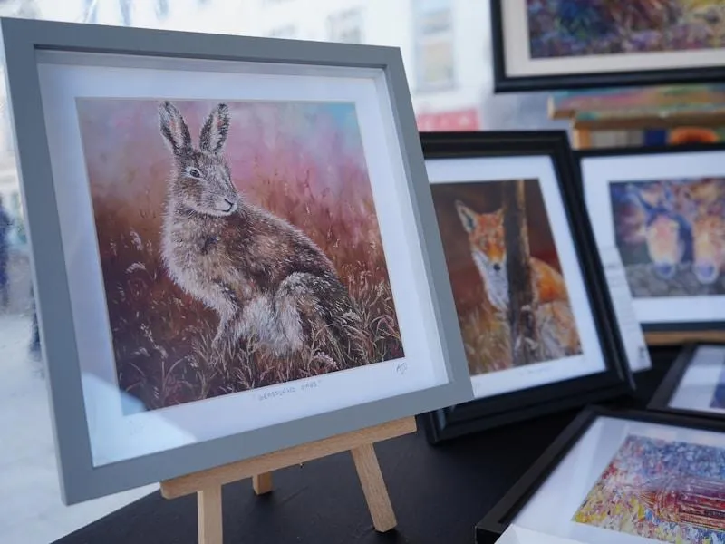 Framed artwork of a hare and other animals on display