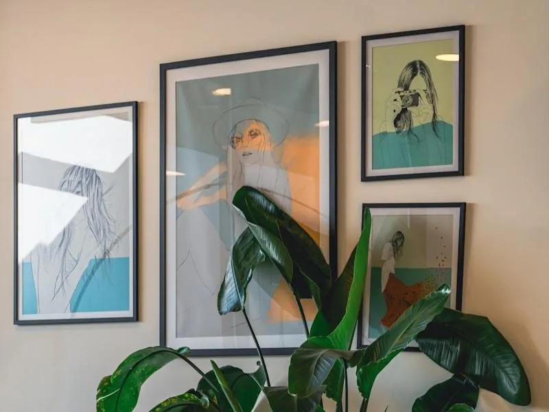 Art prints displayed on a wall with a plant