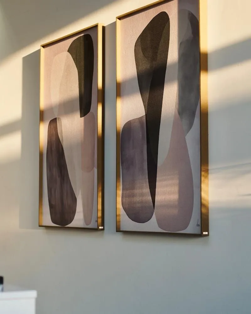 Two abstract paintings with gold frames on wall