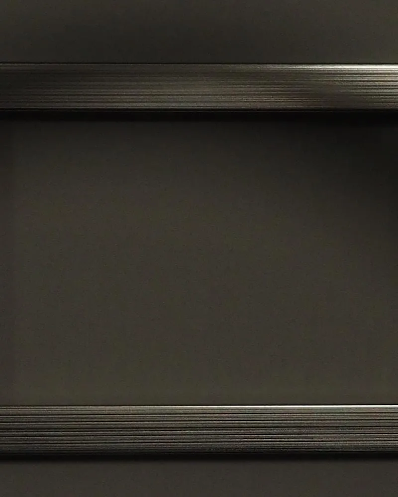 Empty metallic picture frame on a dark wall