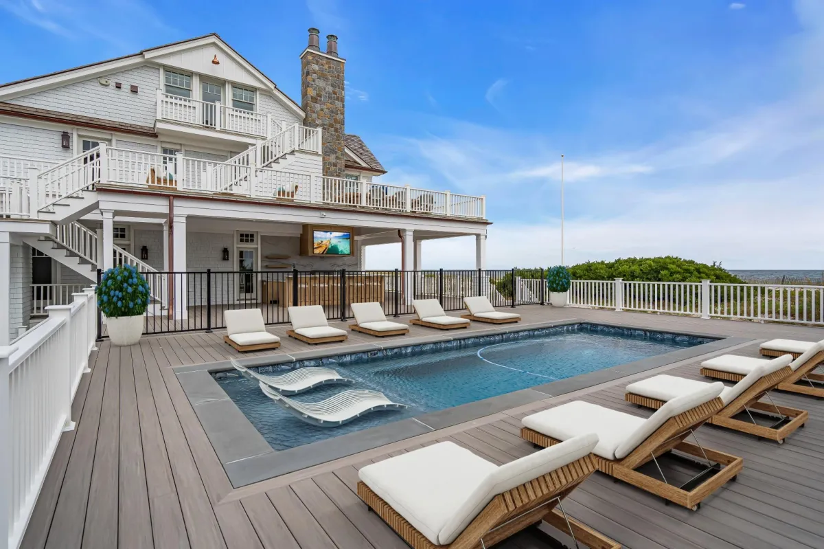 Oceanfront pool terrace with lounge seating, outdoor kitchen, and coastal views