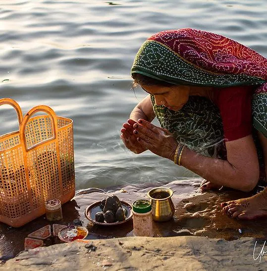 Woman offering prayers at sunrise on the Ganges