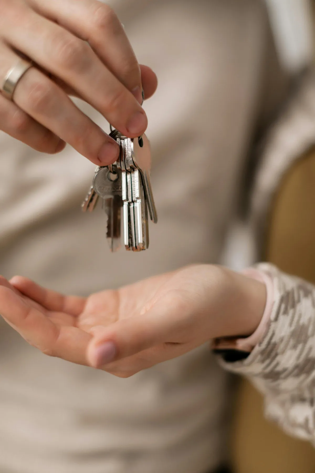Close-up of a person handing over a set of keys to another person, with both hands visible.