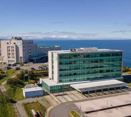Aerial view of a large modern hospital building (Clínica Andes Salud) situated near a coastline