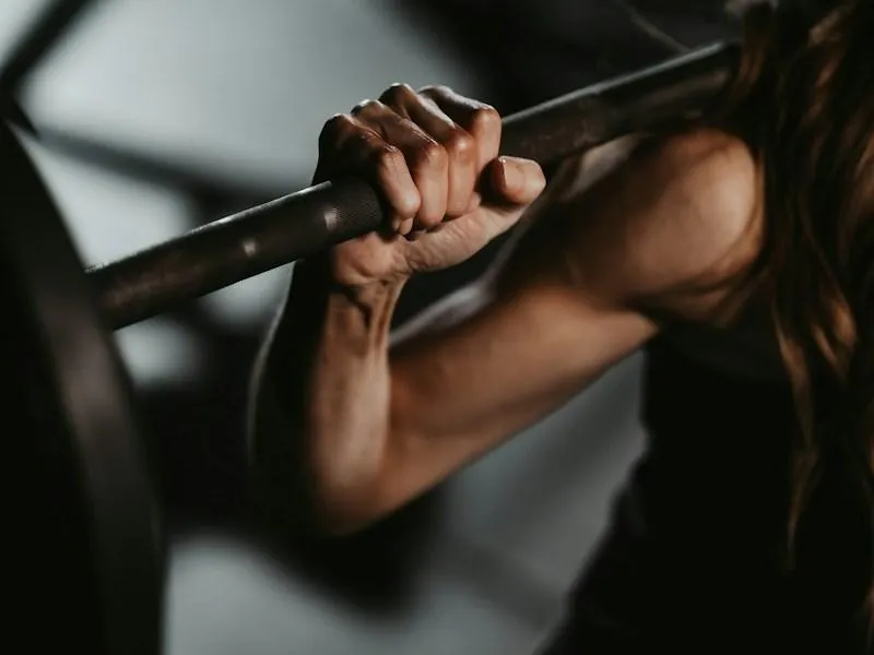A woman lifting a barbell in a gym during a personalized coaching session